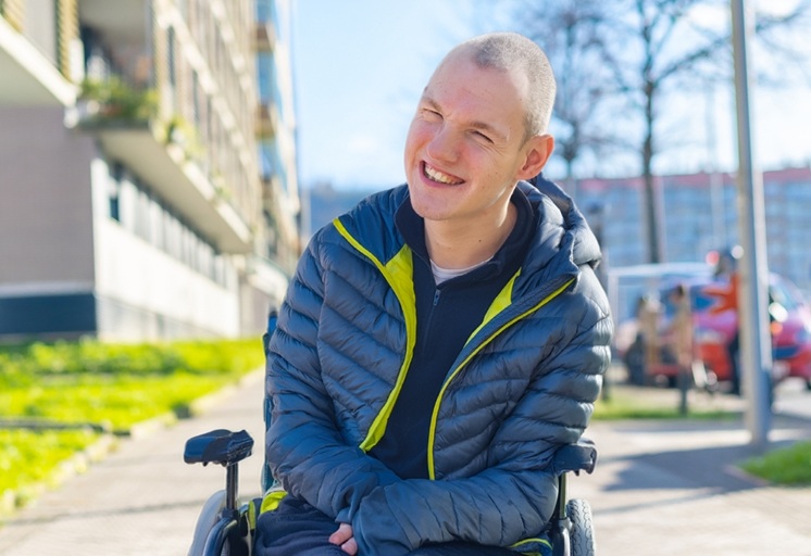 Main in wheelchair outside apartment buildings